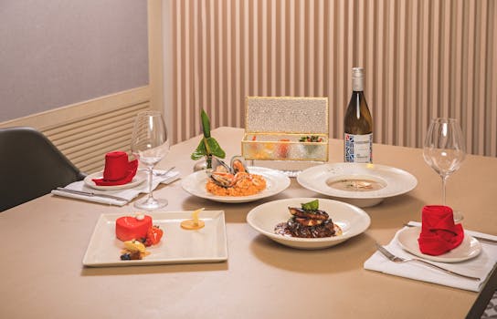 Table élégamment dressée avec plusieurs plats gourmands, dont des fruits de mer, un risotto et un dessert coloré.