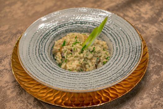 Risotto crémeux aux champignons servi dans une assiette élégante avec une garniture de ciboulette.